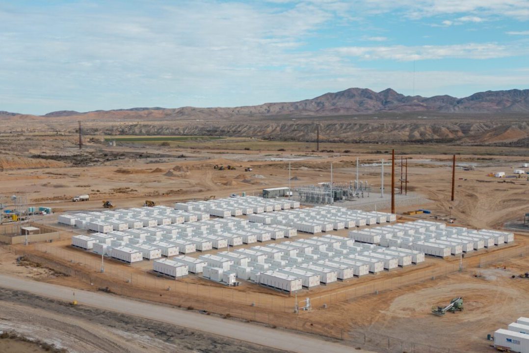 Aerial view of a desert battery storage facility with mountains behind