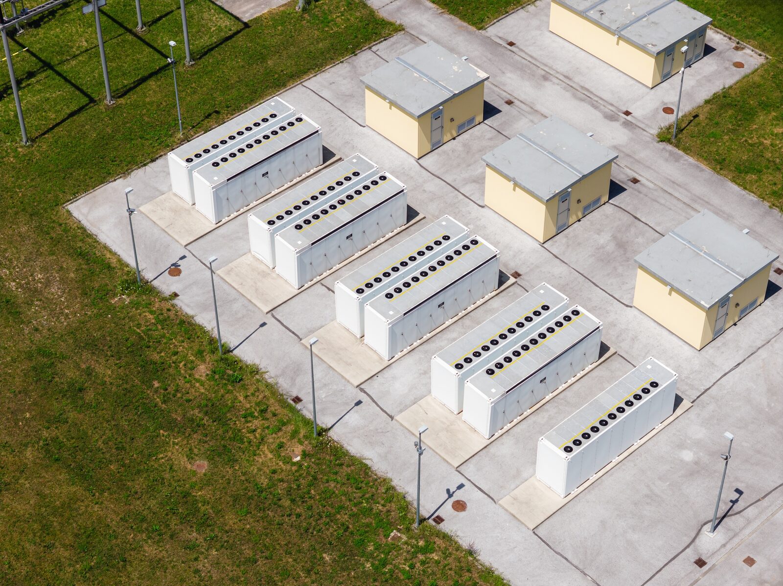 Battery containers and control buildings on a concrete pad beside a switchyard